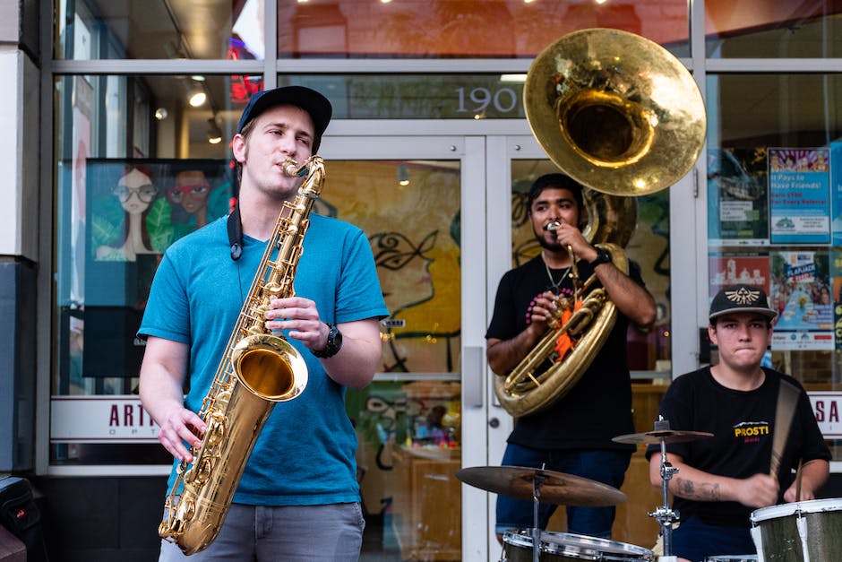 La imagen muestra una banda sinaloense tocando sus instrumentos en un escenario enérgico