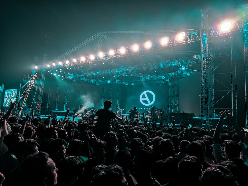 A crowd of people at a rock concert waving their hands in the air and enjoying the music